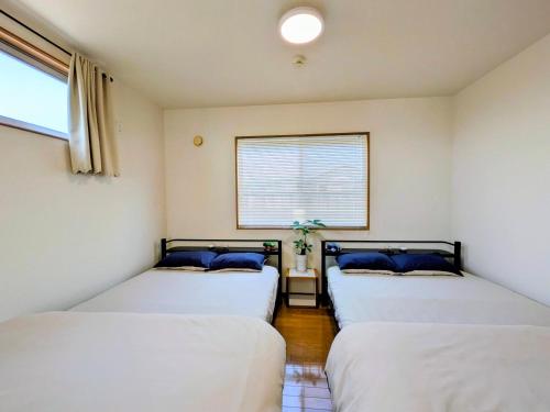 three beds in a room with a window at Frog Inn - Entire House for Private Use in Fujinomiya