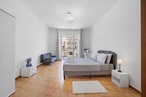 a white bedroom with a bed and a chair at Appartamento Isabella in Verbania