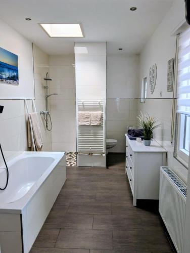 a white bathroom with a tub and a sink at Chez D&D Plus in Eschweiler