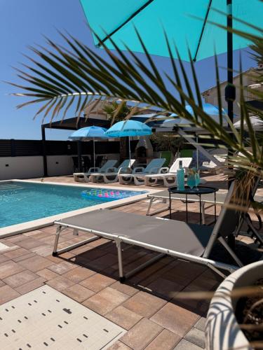 a pool with lounge chairs and a table next to a pool at Luxury Blue Sky in Vir