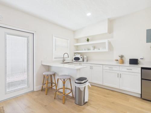 a white kitchen with two stools and a counter at Shell & Shore in Cocoa Beach