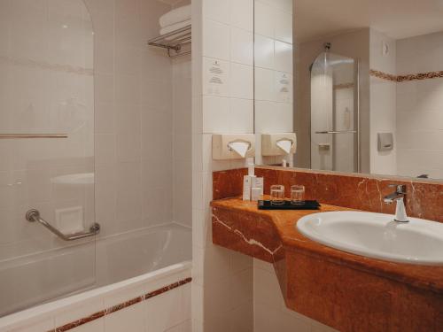 a bathroom with a sink and a bath tub at Millennium Hotel Paris Charles De Gaulle in Roissy-en-France