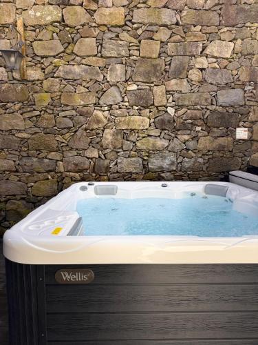 a jacuzzi tub in front of a stone wall at Sete Cidades Quinta Da Queiró in Sete Cidades