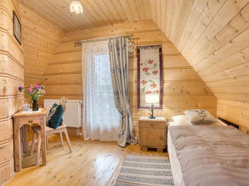 a bedroom with a bed and a desk and a window at Domek Regionalny Bąkowo Chatka in Witów