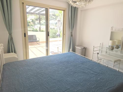 a bedroom with a blue bed and a sliding glass door at Sun Set at Coral Bay in Peyia