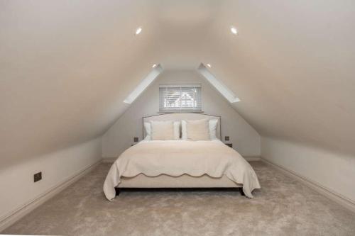 a white bedroom with a bed in a attic at The Annexe in Cobham