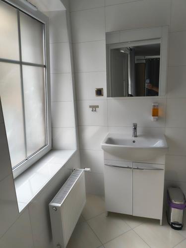 a white bathroom with a sink and a window at Przy Żelaznym Moście in Kłodzko