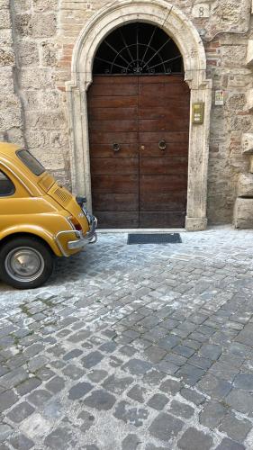 a yellow car parked in front of a wooden door at BnB Centro Centro in Ascoli Piceno