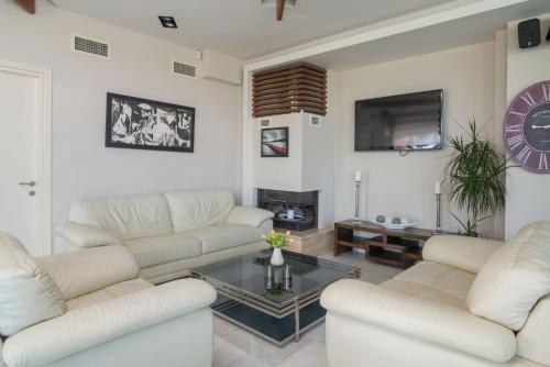 a living room with white couches and a tv at Cosmopolitan Hotel in Paralia Katerinis