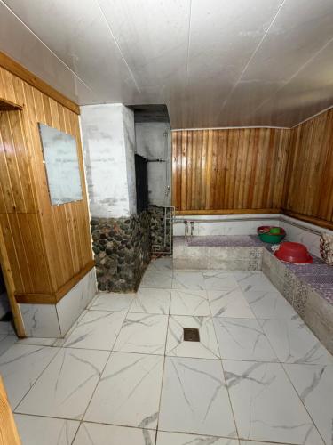an empty kitchen with a tile floor and wooden walls at Bakytzhan hotel in Kurmenty