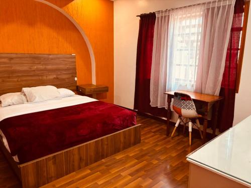 a bedroom with a bed and a desk and a window at Hostal NIZZA in Cuenca