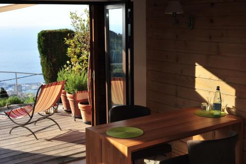- une table et des chaises en bois sur une terrasse avec une bouteille de vin dans l'établissement Chambre à Part, à La Turbie