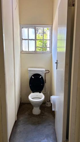 a small bathroom with a toilet with a black seat at Crystal Hostels in Livingstone