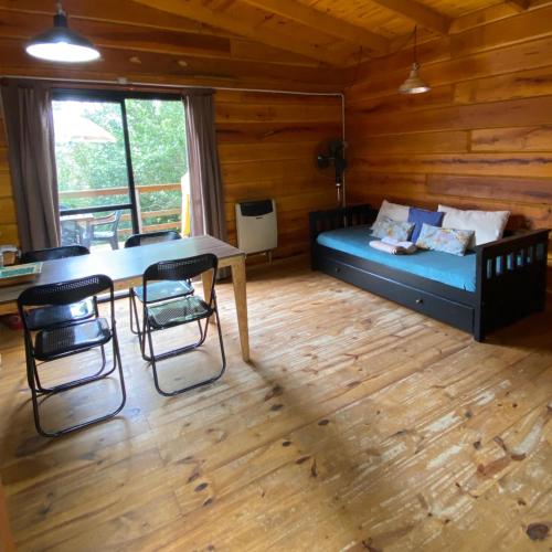 a room with a bed and a table and chairs at Cabañas San Urbano 1 in Villa Yacanto