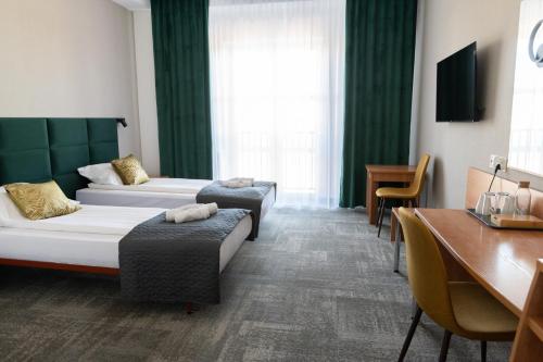 a hotel room with two beds and a desk at Green Hotel in Świebodzin