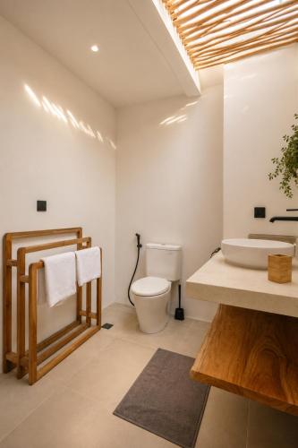 a bathroom with a white toilet and a sink at FinnKai Villas in Sengkol
