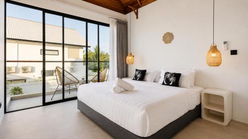 a bedroom with a white bed and a large window at FinnKai Villas in Sengkol