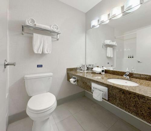 a white bathroom with a toilet and a sink at Coast Abbotsford Hotel & Suites in Abbotsford