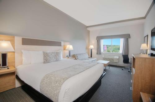 a hotel room with a large bed and a television at Coast Abbotsford Hotel & Suites in Abbotsford
