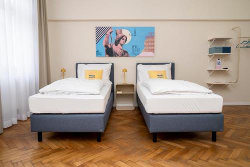 two twin beds in a room with wooden floors at Miki Stays - 200m zum Prater in Vienna