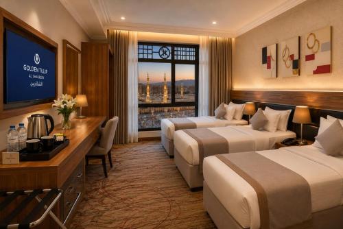 a hotel room with two beds and a television at Golden Tulip Al Shakreen in Medina