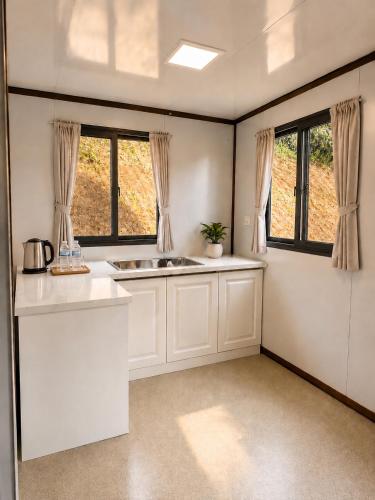 a kitchen with a sink and two windows at Tekoma Resort Taman Negara in Kuala Tahan
