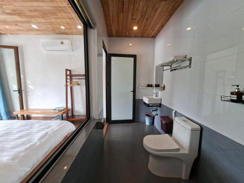 a bedroom with a bed and a toilet and a sink at Vivian riverside cottage - Ninh Bình in Nguyên Ngoại