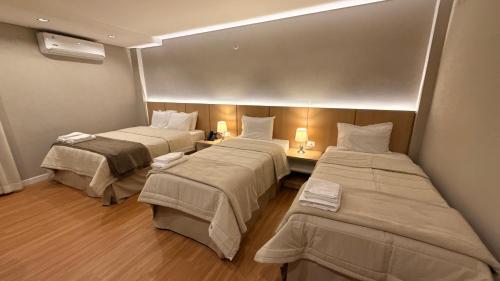 a room with three beds in a room at Di Garda Hotel in Encarnación