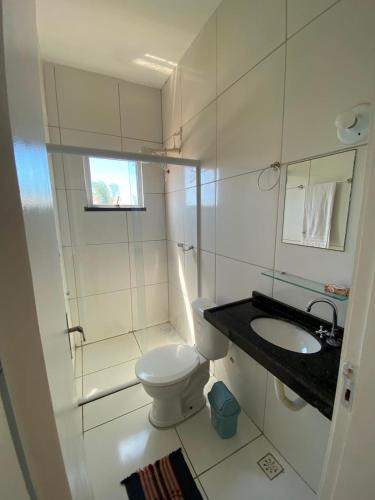 a white bathroom with a toilet and a sink at Refúgio da Praia in Caucaia