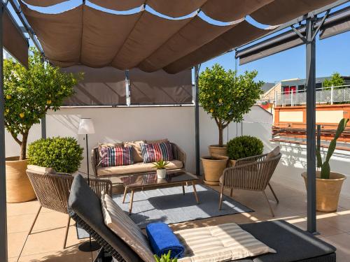 a patio with a couch and chairs under an umbrella at Casa Romana Hotel Boutique in Seville