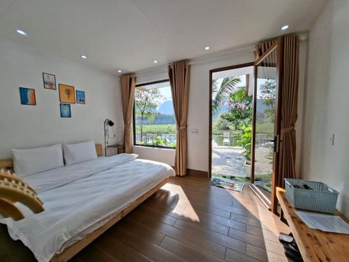 a bedroom with a large bed and a large window at Vivian riverside cottage - Ninh Bình in Nguyên Ngoại