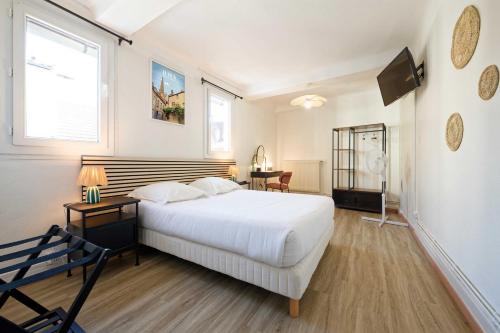 a bedroom with a large white bed and a desk at Hôtel en Ville in Autun
