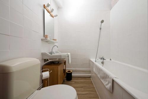 a bathroom with a toilet and a sink and a tub at Hôtel en Ville in Autun