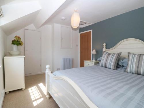 a bedroom with a white bed and a blue wall at 4 Bryn Llan in Pwllheli