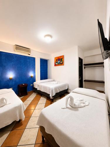 a bedroom with two beds and a blue wall at Hotel Valeria in Granada