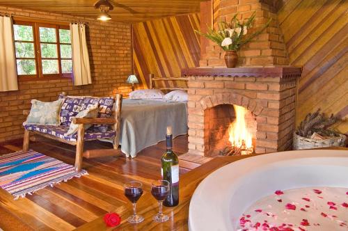 a room with a fireplace and a bed with wine glasses at Pousada Das Araucárias in Visconde De Maua