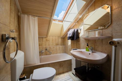 a bathroom with a sink and a toilet and a tub at Ferienwohnung Kampenwand in Bad Endorf