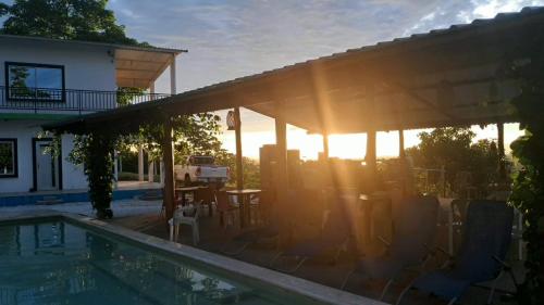 a house with a swimming pool with the sun setting at Finca campestre Wakanda in Doradal