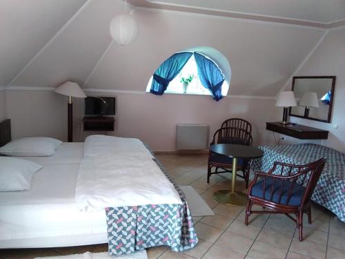 a bedroom with a bed and a table and a window at Castelinho Apartmanház in Gyenesdiás