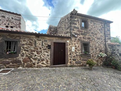 a stone house with a brown door and windows at Prendas Paulilatino in Paulilatino