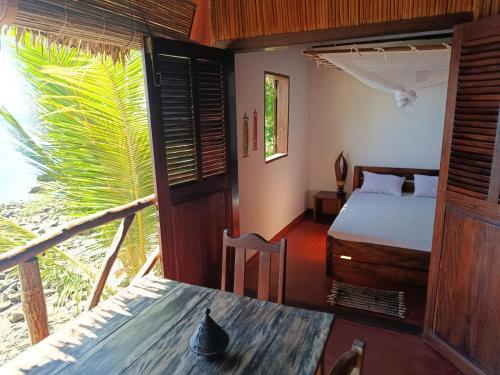 a bedroom with a bed and a table in a room at Manta be à Nosy Komba in Ampangorinana