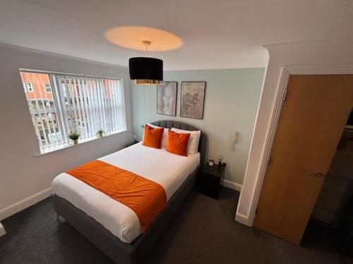 a bedroom with a bed with orange pillows and a window at Aphrodite in Birmingham