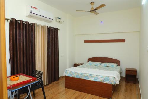 a bedroom with a bed and a table with a tableablish at NJ Grand Villa in Kālapettai