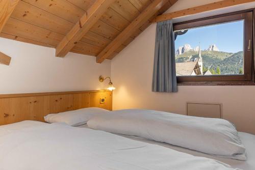 a bedroom with two beds and a large window at Albergo Arnica in Canazei