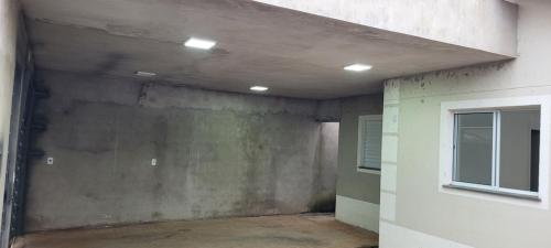 an empty room with a concrete wall and a window at Lar Tranquilo Com Garagem in Pirassununga