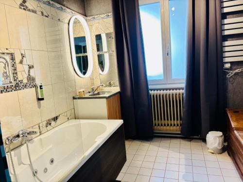 a bathroom with a large tub and a sink at Logis Hôtel-Restaurant Aux Trois Roses in La Petite-Pierre