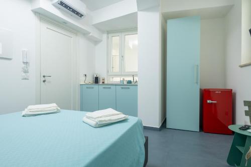 a white kitchen with a bed and a red refrigerator at Le Isole di Anita in Lipari