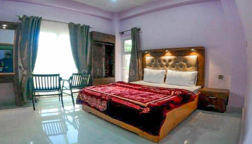 a bedroom with a large bed with a red blanket at Grand palace hotel kumrat in Tāl