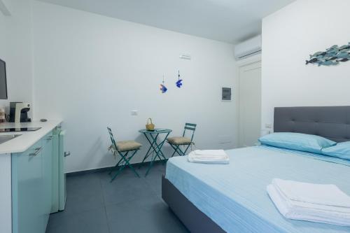 a bedroom with a bed with blue sheets and a kitchen at Le Isole di Anita in Lipari