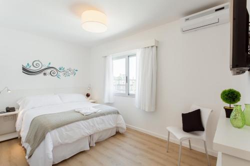 een witte slaapkamer met een bed en een raam bij 20 Hotel in Punta del Este